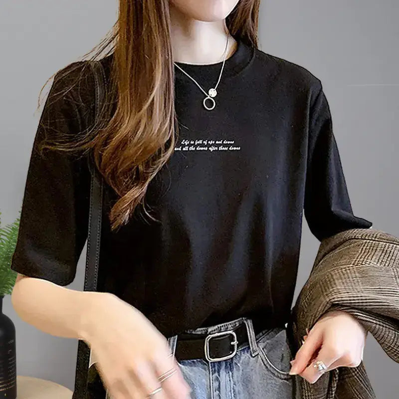 A woman wearing a stylish black Short Sleeve T-Shirt for Women paired with high-waisted jeans and a chic belt.