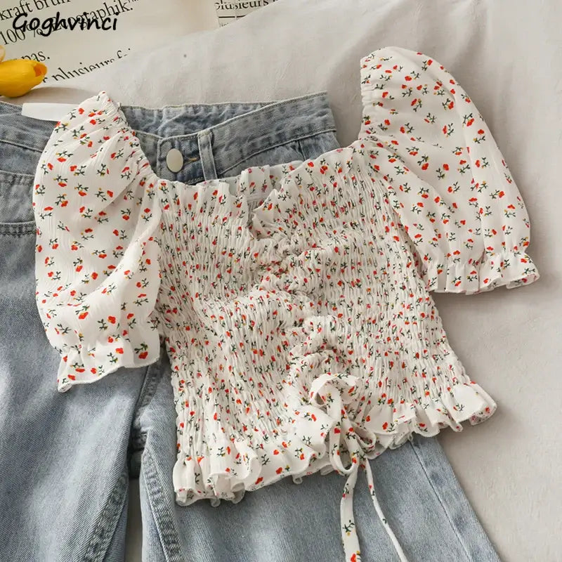 White floral puff sleeve blouse styled with high-waisted denim shorts, perfect for casual summer outfits.