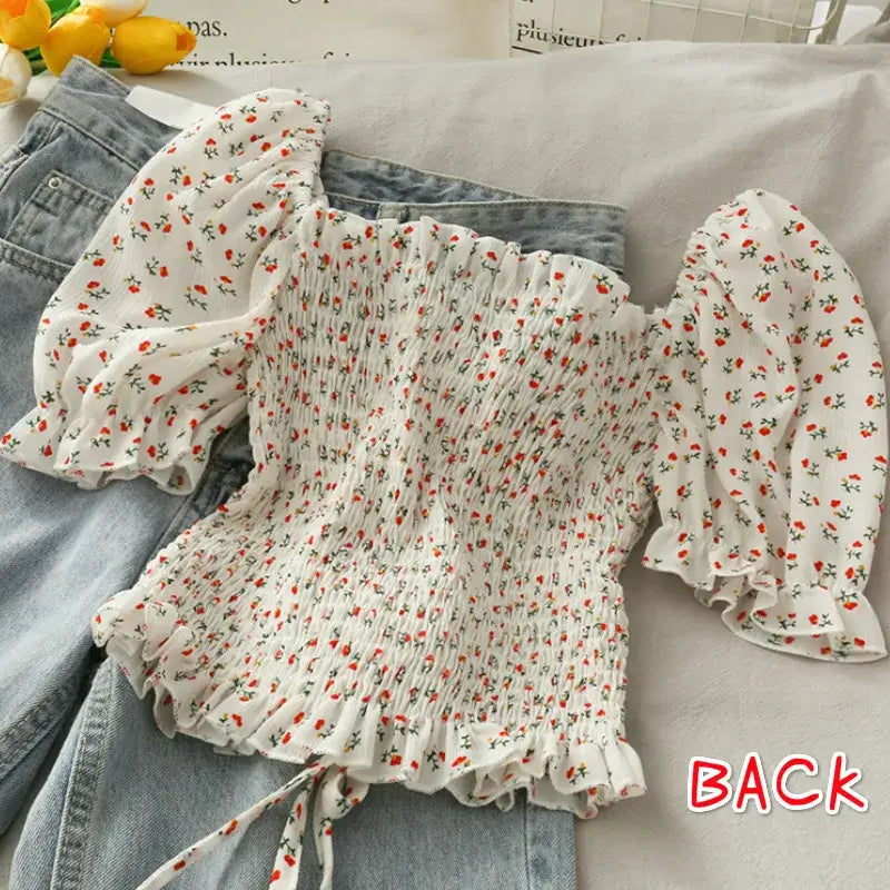 Floral Ruffled Tops for Women - Elegant Chic Crop Top showing back view on a flat lay with denim shorts.