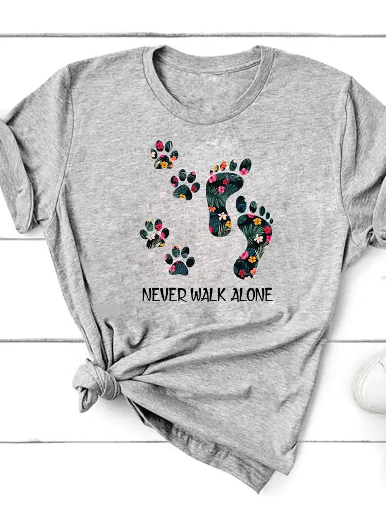 Short Sleeve T-Shirt for Women with floral paw prints and the message "NEVER WALK ALONE" on a gray background.