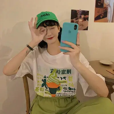 Short Sleeve Women's T-Shirt worn by a woman holding a smartphone and posing with a playful expression.