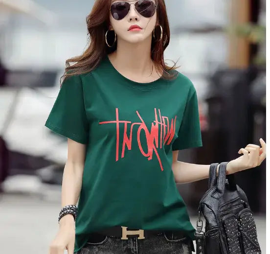 Stylish woman wearing a loose fit Short Sleeve T-Shirt for women in green with graphic text, perfect for casual summer looks.