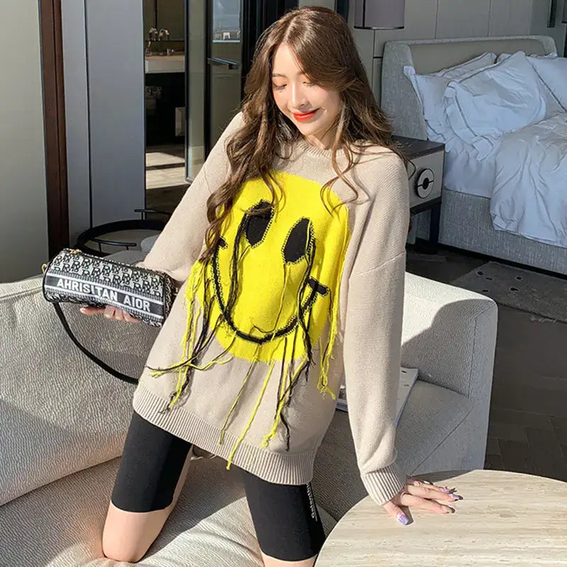 Women's Blissful Smile Pattern Sweater worn by a model, featuring a vibrant smiley face design in a stylish setting.